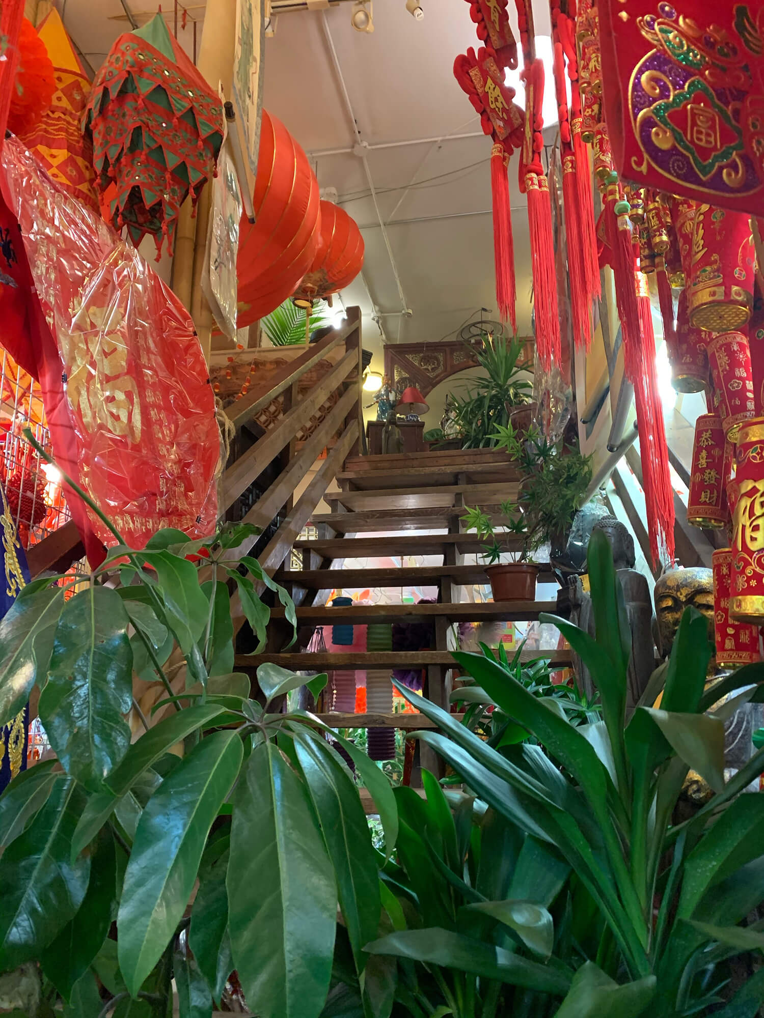 The inside of Bamboo Village has two floors. The wooden staircase is lined with more green houseplants and red decorations.
