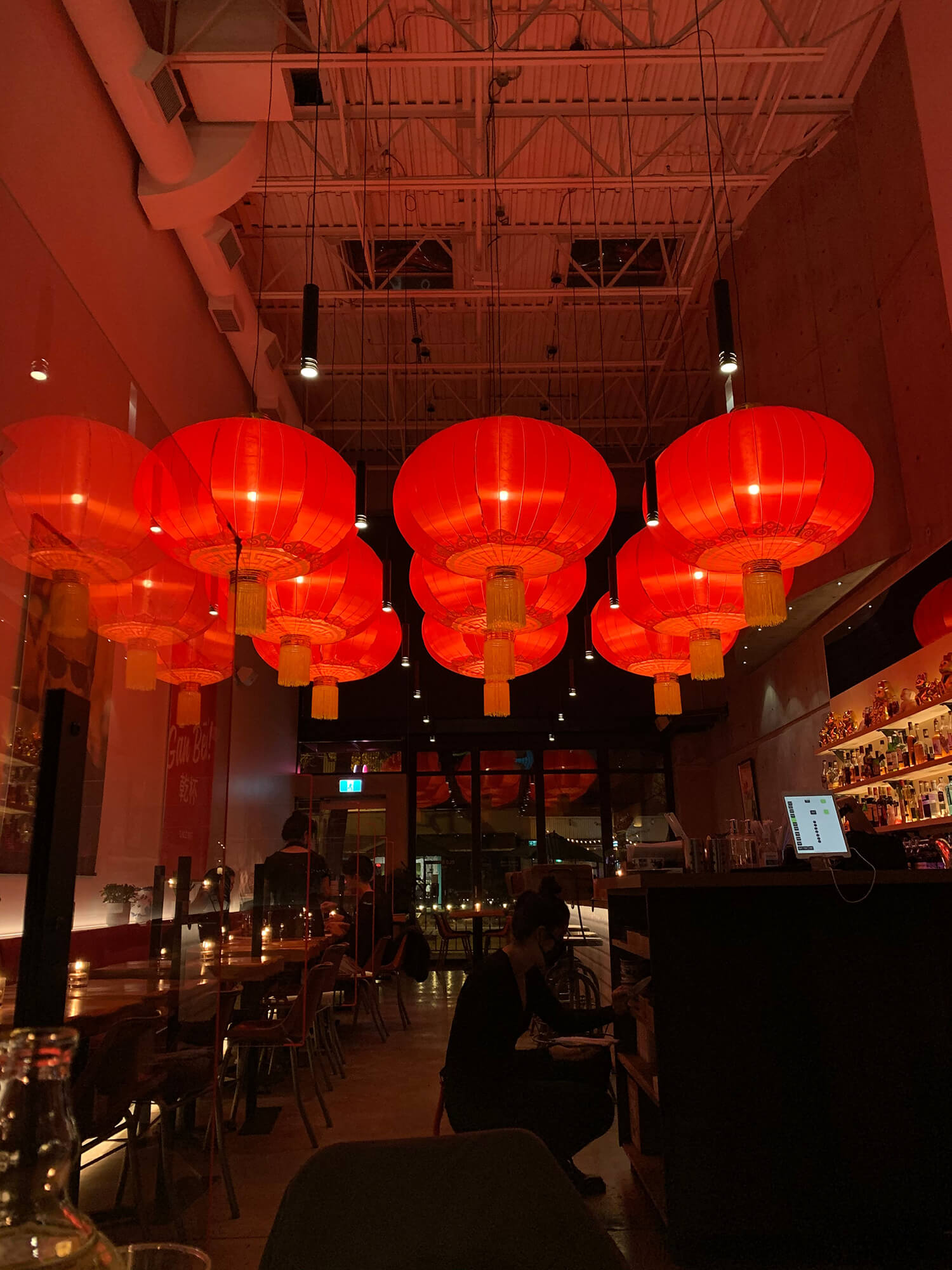Image of nine red Chinese lanterns hung from the ceiling of a dimly lit restaurant in Chinatown at night.